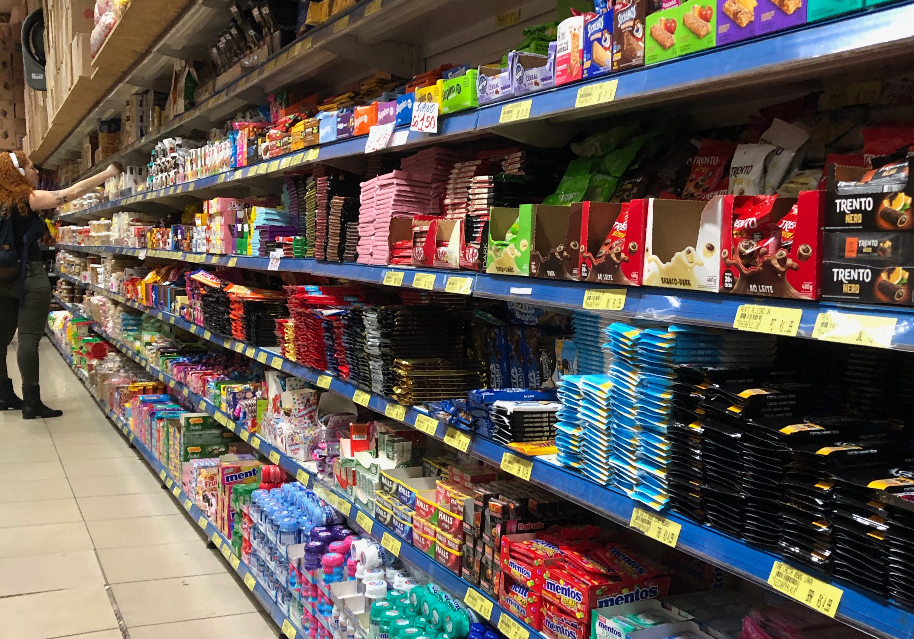 Corredor de supermercado com prateleiras repletas de doces e produtos ultraprocessados